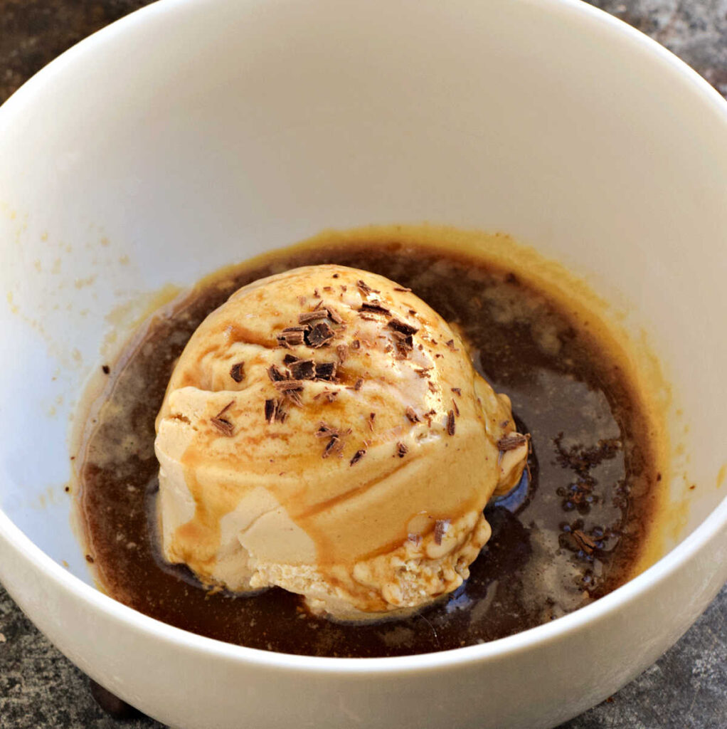 Espresso topped scoop of ice cream with shaved chocolate in a bowl.